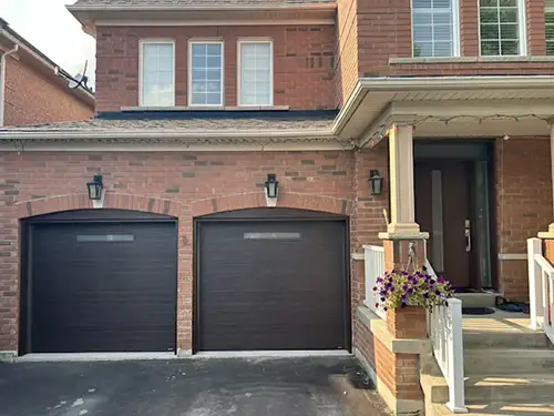 Red brick suburban house with two dark brown garage doors.